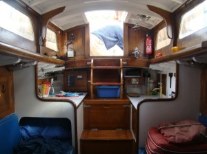 Cabin looking Aft - cooker, sink and freezer locker to the right; chart table, radio and fuse box to the left.  David Dow (previous owner) just visible through the companionway - no doubt varnishing!